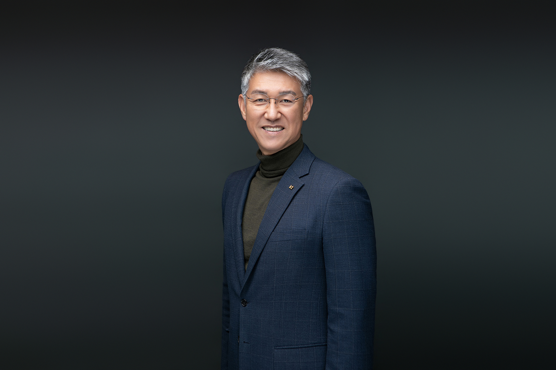 어두운 배경에서 자연스럽게 웃는 남성 임원의 포트레이트